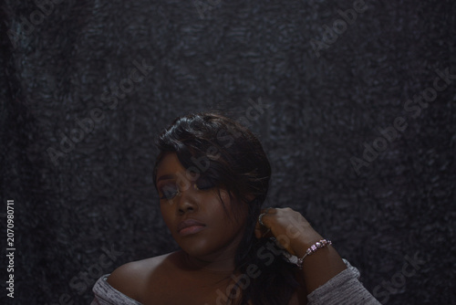 Portrait of a brown skin woman with black smokey eye eyeshadow, an African woman with black eye shadow and a nude lipstick, brown skin woman wearing dark makeup