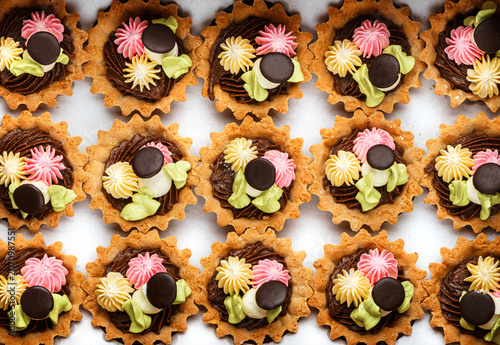 Basket cakes or sand tartlets cake with cream on paper, cake background. Sweets, dessert and pastry, close up, top view