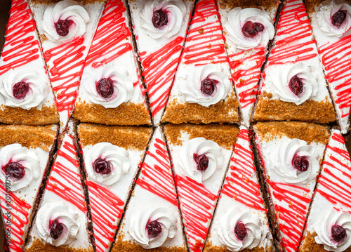 Pieces of cake with cream and cherry, cake background. Sweets, dessert and pastry, close up, top view