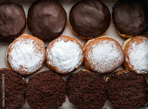 Set of donuts with vanilla, chocolate icing, powdered sugar and chocolate chips on paper, donut background. Sweets, dessert and pastry, close up, top view