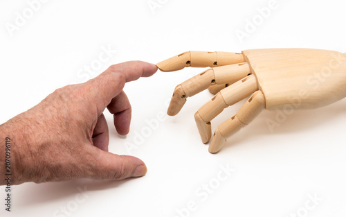 Mano humana y de marioneta tocandose con los dedos indice, aislado en blanco