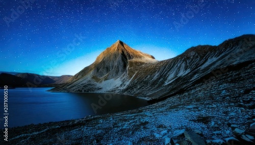 Majestic mountain peak reflecting in serene lake under starry night sky.