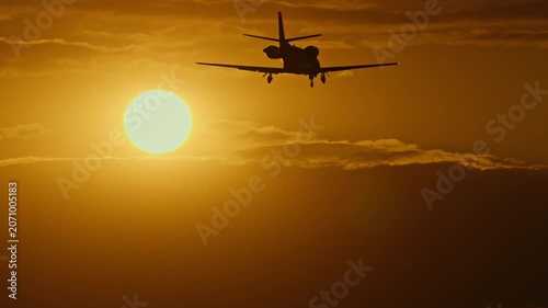 Silhouette of a private jet flying against a vibrant sunset sky