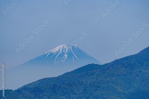 青空に映える残雪の富士山と手前の新緑の山並み