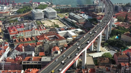 Aerial drone shot of busy bridge traffic above Lisbon urban cityscape in Portugal. Elevated roadway crossing residential district with modern buildings