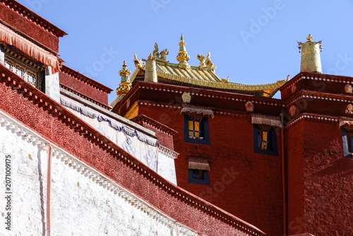 Foto Golden rooftop ornaments crown the crimson walls of Ganden Monastery, a sacred T