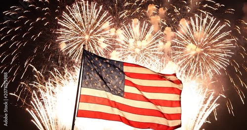 American flag waving with bright fireworks exploding in the night sky.
