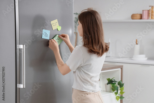 Young woman putting sticky ...