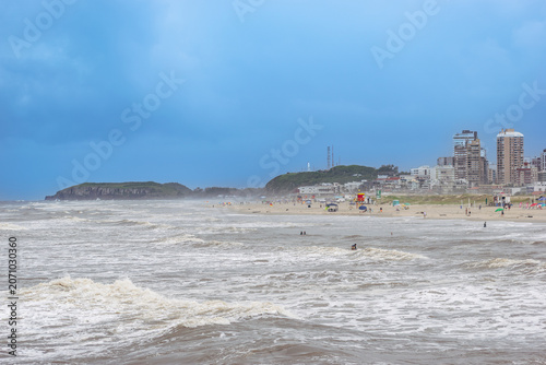 Photos Fuertes olas del océano rompiendo en una playa de arena con edificios de la ciud