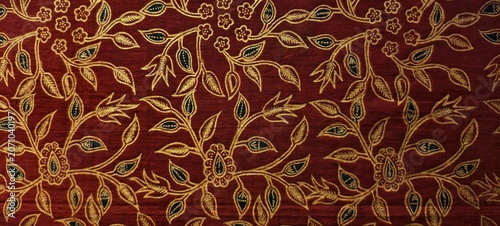 Fotografie Richly patterned batik fabric featuring intricate golden floral embroidery on a deep red background