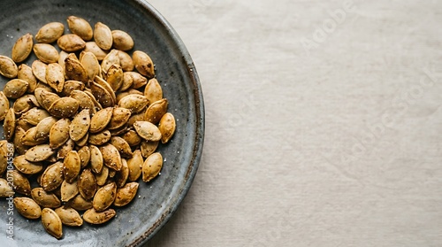 Roasted pumpkin seeds in a rustic bowl on neutral linen background