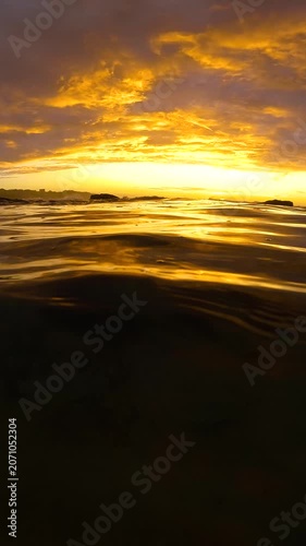 Slow motion video of a spectacular sunrise viewed from the Bogey Hole at Bronte Beach, Sydney, Australia, with calm rippling water reflecting golden morning light.