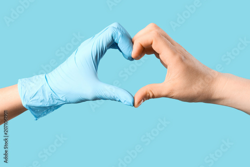 Fotografie Hands forming a heart shape with one wearing a blue glove