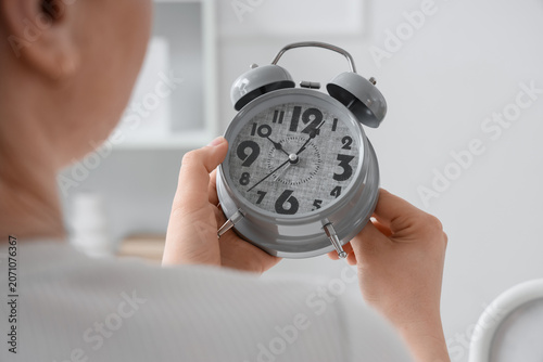 Woman changing alarm clock ...