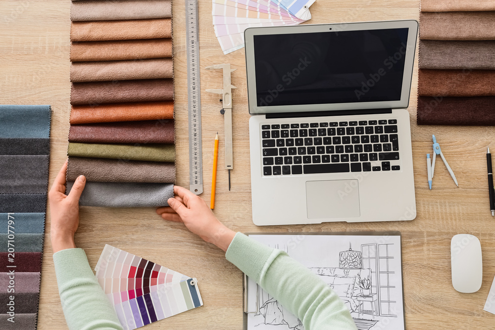 Obraz premium Female interior designers hands with fabric samples and blank laptop on table, top view