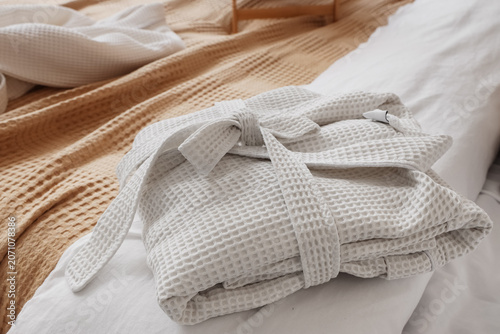 Folded bathrobe on bed in r...