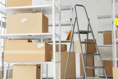 Tableau sur toile Shelf units with cardboard boxes and stepladder in warehouse