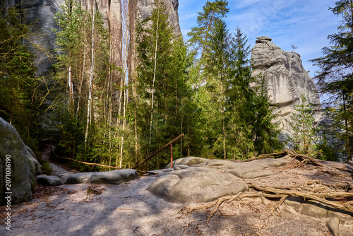 Obraz na płótnie Majestic rock cliffs and forest trail under blue sky in spring