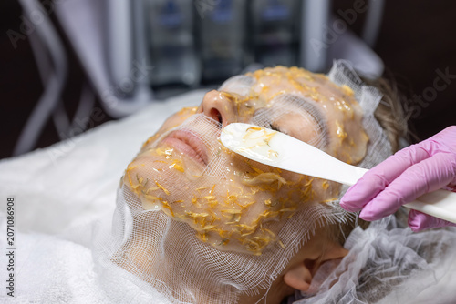 Schilderij op canvas Alginate facial mask with calendula petals being applied during professional skincare treatment