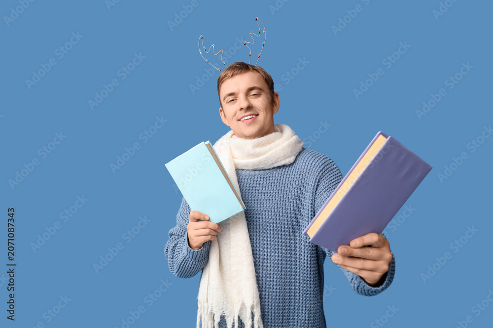 Naklejka premium Young man with books on blue background. Christmas celebration