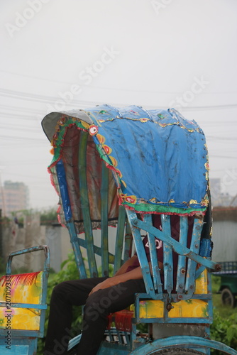 Foto Colorful manual cycle rickshaw with blue canopy in urban setting, three wheeler