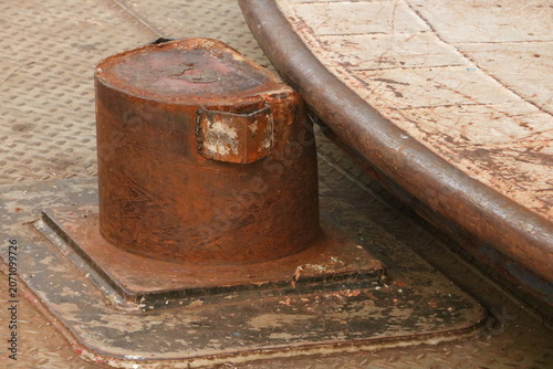 Foto Weathered cylindrical iron bollard on a rough industrial textured surface with i