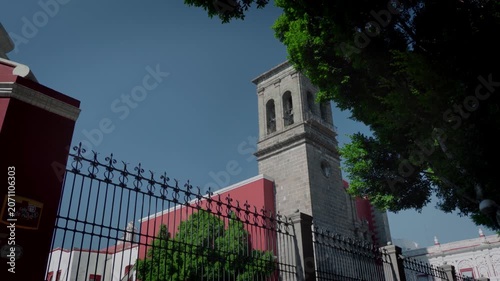 Santo Domingo Church facade illuminated by strong sunlight in Puebla historic center featuring twin towers ornate entrance and colonial architecture in a vibrant urban setting