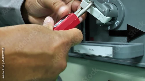 Close-up of a worker securing an electrical disconnect switch with a Lockout Tagout device, demonstrating compliance with industrial safety procedures, energy isolation, and workplace hazard preventio