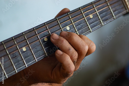 Obraz na plátně Close up of a musician hand pressing fingers on steel strings on an acoustic gui