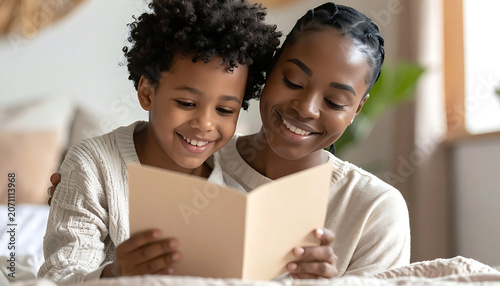 Mother and son smiling while reading a greeting card together, happy family moment, warm indoor lighting