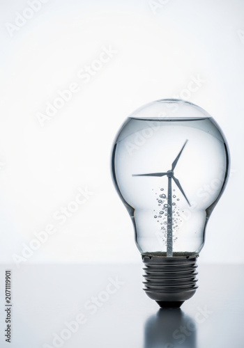Green energy concept with hydrogen production symbolized by wind turbine inside light bulb with water and bubbles