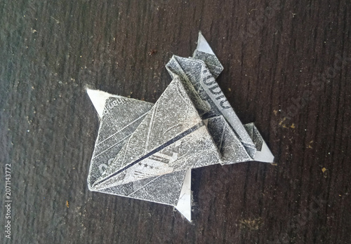 origami paper frog made from printed newspaper on a dark wooden background