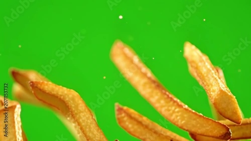 Closeup of Crispy French Fries Moving Against Bright Green Background