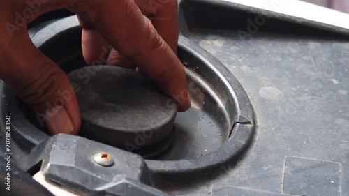 Person checking fuel level by opening a motorcycle fuel tank. Close up of vehicle inspection, transportation preparation, and motorcycle maintenance.