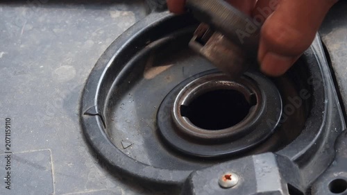 Person checking fuel level by opening a motorcycle fuel tank. Close up of vehicle inspection, transportation preparation, and motorcycle maintenance.