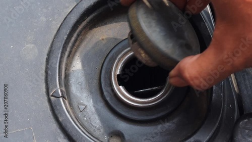 Person checking fuel level by opening a motorcycle fuel tank. Close up of vehicle inspection, transportation preparation, and motorcycle maintenance.