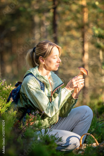 Smiling woman mushroomer forager found fresh edible boletus mushrooms in autumn pine forest, happy female hiker on traditional fall porcini harvest in wild woods, autumn hobby and leisure activity.