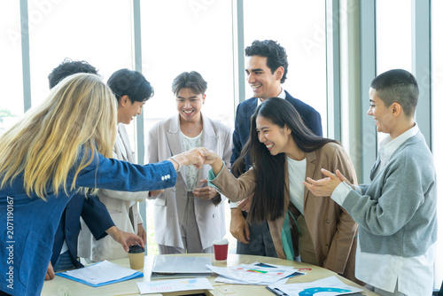 Group of business people joining hands together in office. Teamwork concept.
