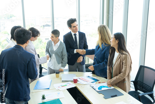 Group of business people joining hands together in office. Teamwork concept.