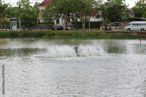 Fotografia Water aerator machine churning a pond surface with splashing water