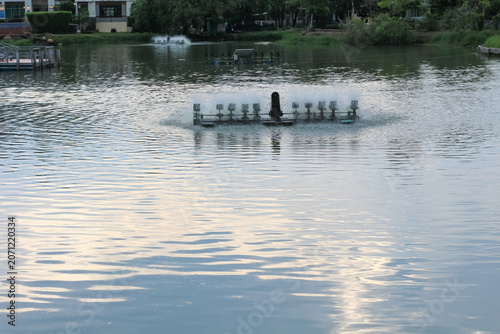 Foto Water aerator machine spinning in a calm lake, creating ripples and splashes
