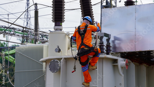 Obraz w ramie Electrical technician climbing transformer during maintenance work