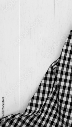 Wrinkled black gingham fabric on rustic white wood plank background, with copy space.