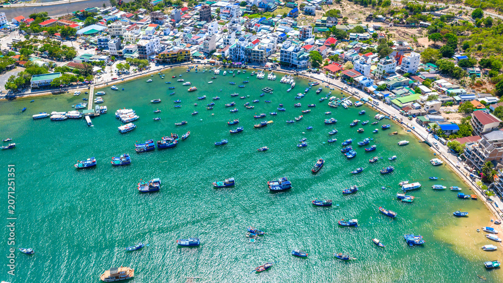 Fototapeta premium Breathtaking aerial view of Vinh Hy Bay, Vietnam, featuring emerald waters, colorful fishing boats, coastal villages, and rugged mountains. 
