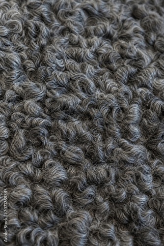 Close-up detail of a Karakul lamb fur rug with tight curly texture.