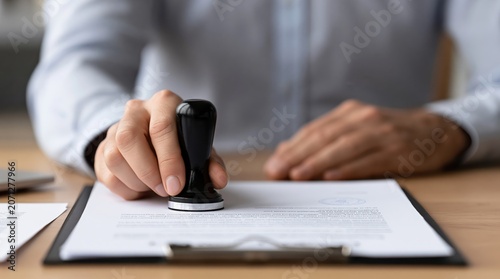 Hand of person stamping official document on clipboard in office