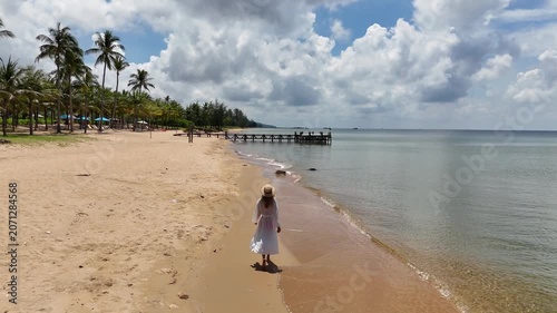 Young woman walking along a tropical beach on a sunny day