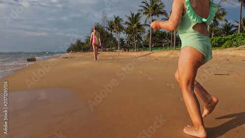 Young girl running along sandy beach near ocean at tropical resort