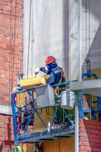 A man finishes the facade on a summer day