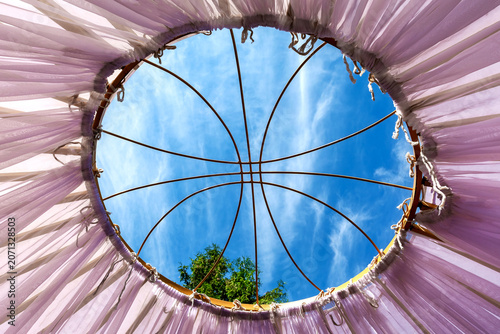 Through the opening in the roof of the yurt, one can see the clear blue sky.